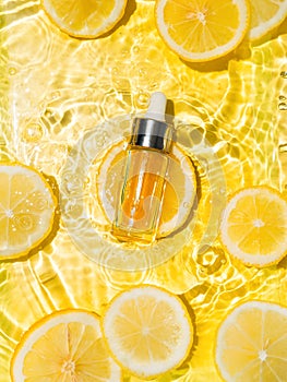 Cosmetic bottle in water, lemon slices, yellow