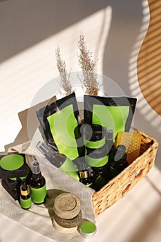 Cosmetic bottles, jars and doy packs in wicker basket with green space for brand.