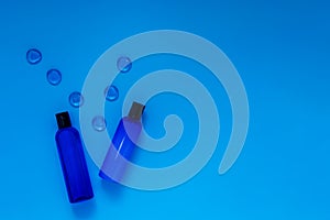 Cosmetic bottles with refreshing shampoo and lotion on a blue background, top view. Packaging for branded products.Blue on blue