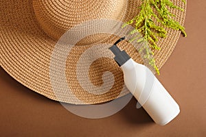 cosmetic bottles and straw hat on brown background