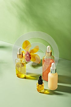 Cosmetic care products in glass bottles with orchid flowers - serums, cream, gel, oils. Concept for face and body care