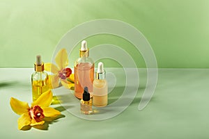 Cosmetic care products in glass bottles with orchid flowers - serums, cream, gel, oils. Concept for face and body care