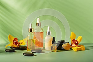 Cosmetic care products in glass bottles with orchid flowers - serums, cream, gel, oils. Concept for face and body care