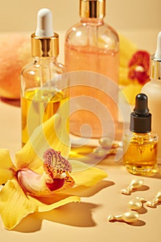 Cosmetic care products in glass bottles with orchid flowers - serums, cream, gel, oils. Concept for face and body care