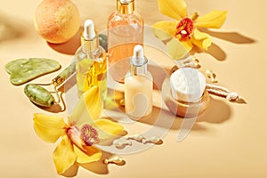 Cosmetic care products in glass bottles with orchid flowers - serums, cream, gel, oils. Concept for face and body care