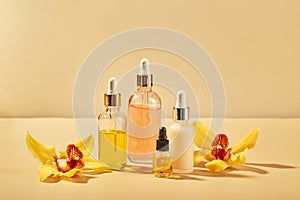 Cosmetic care products in glass bottles with orchid flowers - serums, cream, gel, oils. Concept for face and body care