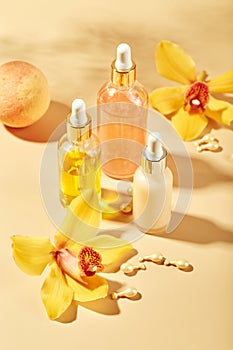 Cosmetic care products in glass bottles with orchid flowers - serums, cream, gel, oils. Concept for face and body care