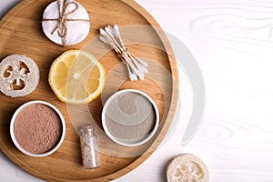 Cosmetic clay facial masks, sea salt, lemon loofah on wooden background.