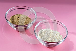 Cosmetic clay in glass bowls on pink background