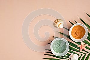 Cosmetic clay masks on beige background with tropical palm leaf and seashells. SPA natural organic beauty products, summer facial