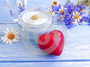Cosmetic cream, chamomile lotion flower, natural cornflower, heart wooden background