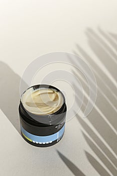 Cosmetic cream container with face or body cream on neutral background