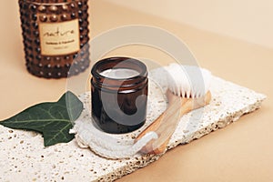 Cosmetic cream in a jar and face brush on natural stone, aroma candle. Spa and wellness, zero waste concept. Close up