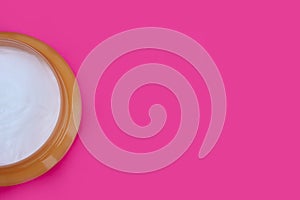 Cosmetic cream in a jar on a pink background, topview. Copy space for text