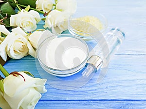 cosmetic cream organic , rose flower, salt on a blue wooden background