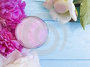 Cosmetic cream, peony flower on a blue wooden background