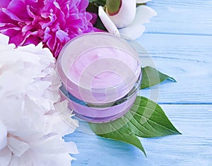 Cosmetic cream, peony flower lotion on a blue wooden background