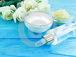 cosmetic cream, rose flower, salt on a blue wooden background