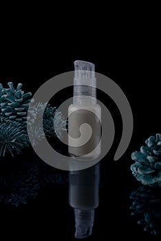 cosmetic cream in a white bottle on a black background with spruce and cones