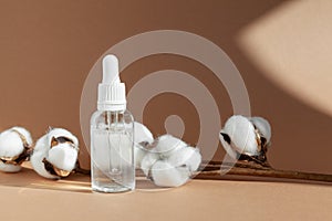 Cosmetic dropper bottle with cotton for serum, micellar toner and emulsion on brown background. Beauty product