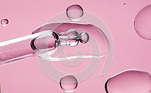 Cosmetic dropper with serum, beauty cosmetics dripping, on pink background. Macro shot