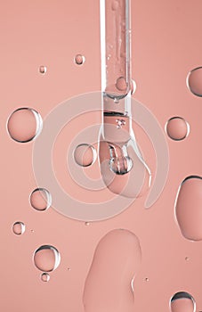 Cosmetic dropper with serum, beauty cosmetics dripping, on pink background. Macro shot