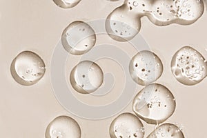 Cosmetic drops. Drops of liquid transparent gel with bubbles on a brown background