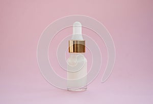 Cosmetic face serum in a blnom bottle on a pink background