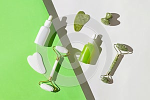 Cosmetic facial kit for home skin care and spa. Face rollers and gua sha massagers made from jade, bottles of serum or essential