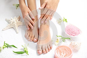 Cosmetic, flowers and woman touching her smooth feet on white towel, closeup.