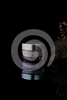 cosmetic forest face cream with pine on a black background