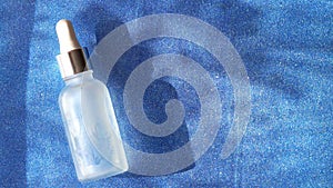 Cosmetic hydrating serum in a glass bottle with pipette close up. Hyaluronic acid on the white background top view with