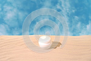 Cosmetic jar on sandy podium against sky background with clouds. Concept of cosmetic products. Front view. Desigh for