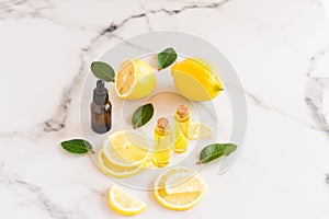 Cosmetic lemon oil and citrus essential oil on a marble table. fruits of fresh lemon and melisa leaves. cosmetics of nature in