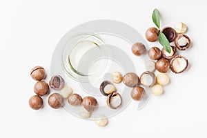 Cosmetic macadamia oil and heap of nuts on white table top view. photo