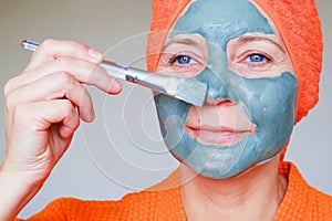 Cosmetic mask on the face. Close up portrait of beautiful young woman with towel on her head having skin care procedure. She is