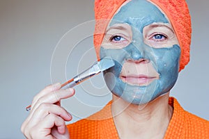 Cosmetic mask on the face. Close up portrait of beautiful young woman with towel on her head having skin care procedure. She is