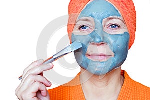 Cosmetic mask on the face. Close-up portrait of a beautiful young woman with a towel on her head having skin care treatments. She