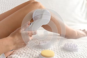 Cosmetic massage machine. At home on a white sofa with light.