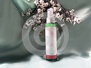 Cosmetic mist with flowers and green background