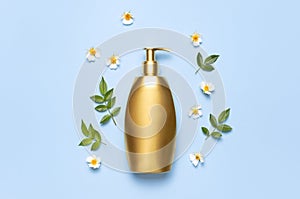 Cosmetic mock up gold bottles. Cosmetics, spring white flowers green leaves on blue background. Cosmetics springtime summer
