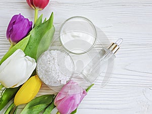 Cosmetic moisturizer cream, salt, beauty tulip flower on a white wooden background