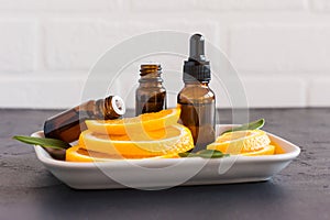 Cosmetic orange oil in a bottle with a dropper and two bottles of essential oil against the background of orange slices