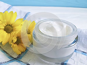 Cosmetic cream organic morning skincare ointment yellow chrysanthemum flower white wooden, daisy, towel