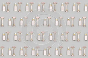 Cosmetic pattern. Crystal rose quartz facial roller and anti-aging collagen, serum in glass bottle on grey background. Facial