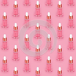 Cosmetic pattern. Pink anti-aging facial serum in transparent glass bottle with gold pipette on pink background. Hydrating serums