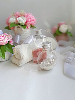 Cosmetic pearl bottles, towel, bouquet of soap flowers on white background.
