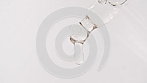 Cosmetic pipette with drops of oil close up on white background