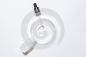 Cosmetic pipette serum on a petri dish on white background. Cosmetology and pharmaceuticals concept. Acid peeling, face oil,