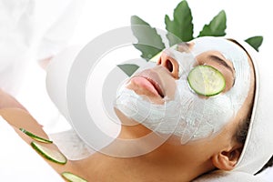 Cosmetic procedure woman's face in the mask mitigating and cucumber slices on eyes